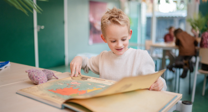 Jongen kijkt nieuwsgierig in boek