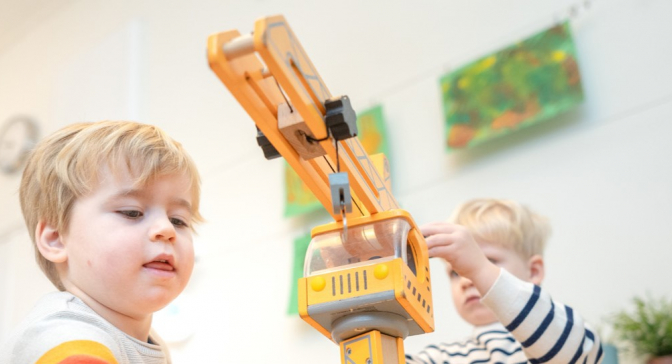 Jongetjes spelen met speelgoed hijskraan op kinderdagverblijf